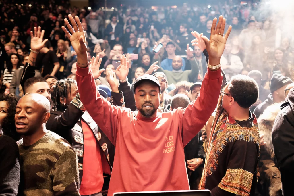 Kanye West at his album release event with hands in the air